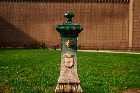 Ancient drinking water fountain in historical touristic center in Milano, Italy. Monumental structure with sign of cross on it in the castle.