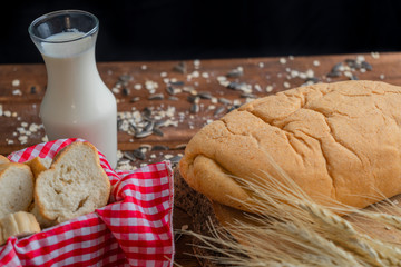 Fresh bread and wheat on wood