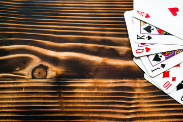 Classic playing cards on dark brown wooden table. Scattered cards. Texture.