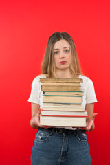 The girl in jeans and T-shirt stands and holds a book, she is tired and has no hunting learns, home learning