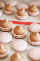 Brown macaroons with chocolate ganache on silicone mat. Cooking process. Selective focus.