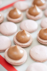 Brown macaroons with chocolate ganache on silicone mat. Cooking process. Selective focus.