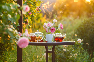 Jam in glass jar. Romantic dinner in the garden under a rose bush Pierre de Ronsard. Summer time