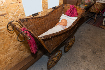 Close-up view on old infant cradle. Traditional cradle with toy of baby in the room. Old cradle on wheels