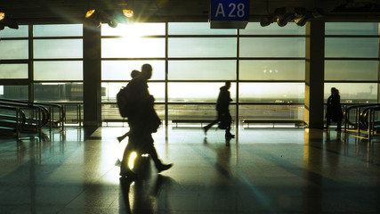 SILHOUETTE: Unrecognizable tourists hurry down an airport terminal at sunrise.