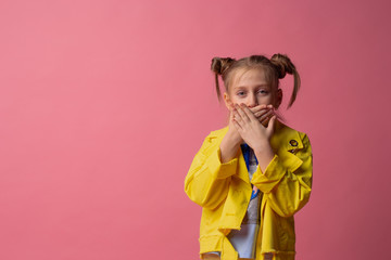 girl shut her mouth with her hands in yellow clothes on pink background. concept of silence