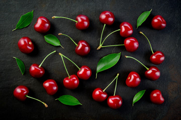 Cherries background. Cherries on black top view. Cherry background. Sour cherry with leaves on black background.