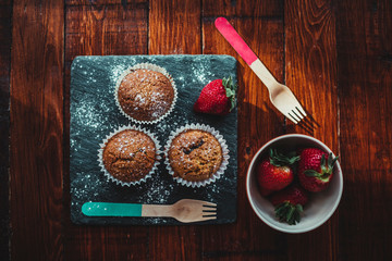 Appetizing Chocolate Muffins made with wholemeal flour and brown sugar with strawberries for a healthy breakfast.