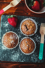 Appetizing Chocolate Muffins made with wholemeal flour and brown sugar with strawberries for a healthy breakfast.
