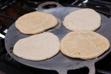 Nutritious handmade corn tortilla cooked on a metal griddle on a gas stove in a Guatemalan home.