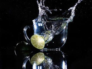 glass mug of water with lime splashing in