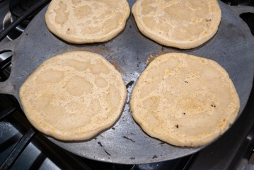 Nutritious handmade corn tortilla cooked on a metal griddle on a gas stove in a Guatemalan home.