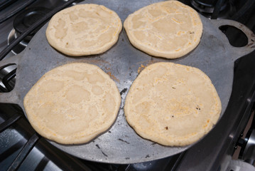 Nutritious handmade corn tortilla cooked on a metal griddle on a gas stove in a Guatemalan home.
