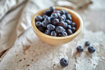 Image of blueberries in wooden bowl on rustic village table.