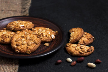 Homemade peanut cookies on a brown plate with raw peanuts in background