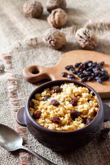 Sweet millet porridge with dark raisins in ceramic rustic bowl