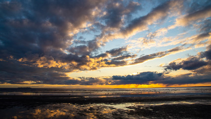 Fototapeta na wymiar Beautiful clouds in the sunset rays on the sandy beach of the sea.
