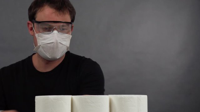 the man in protective mask and glasses to build a pyramid out of toilet paper