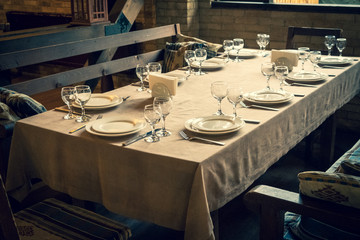 The served table in the restaurant. Clean dishes and appliances on the tablecloth in a cafe. Shiny transparent glasses. White plates. Prepared for the reception of guests. High service.