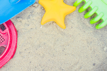 Fototapeta na wymiar Toys for the sandbox. Children's toys in the sand. Shovel, rake and asterisk. Place for your text.