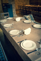 The served table in the restaurant. Clean dishes and appliances on the tablecloth in a cafe. Shiny transparent glasses. White plates. Prepared for the reception of guests. High service.