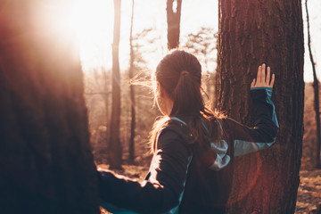 Young woman standing between two trees and watching sunset, beautiful colors, lens flares,...
