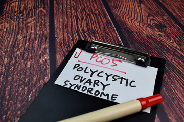 PCOS. Polycystic Ovary Syndrome write on sticky notes. Isolated on wooden table background