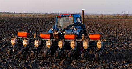 Tractor with a seeder working on arable land. Agricultural work. Spring sowing of grain crops.