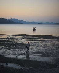 Fototapeta na wymiar Fisherman trying to get to the boat at beautiful sunset on the beach. Ko Yao Noi Thailand.