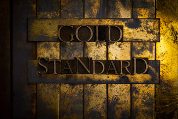 Photo of real authentic typeset letters forming Gold Standard text on vintage textured grunge copper and gold background