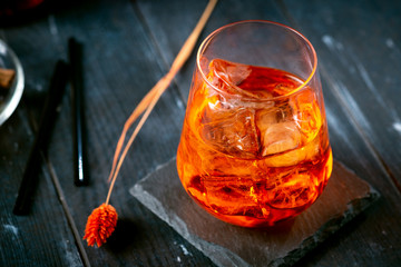 An Aperol syringe with orange and ice in glass on a dark wooden background