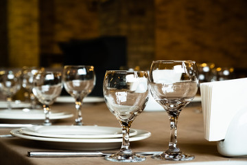 The served table in the restaurant. Clean dishes and appliances on the tablecloth in a cafe. Shiny transparent glasses. White plates. Prepared for the reception of guests. High service.