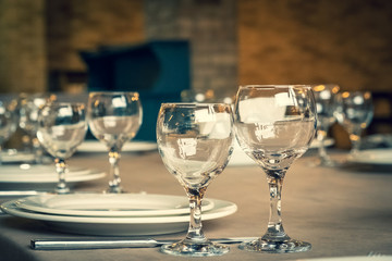 The served table in the restaurant. Clean dishes and appliances on the tablecloth in a cafe. Shiny transparent glasses. White plates. Prepared for the reception of guests. High service.