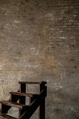 Dark wooden stair near to an old brick wall. Short stair. Vertical photo