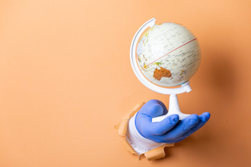 doctor's hand with blue glove clutching a world ball