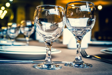 The served table in the restaurant. Clean dishes and appliances on the tablecloth in a cafe. Shiny transparent glasses. White plates. Prepared for the reception of guests. High service.