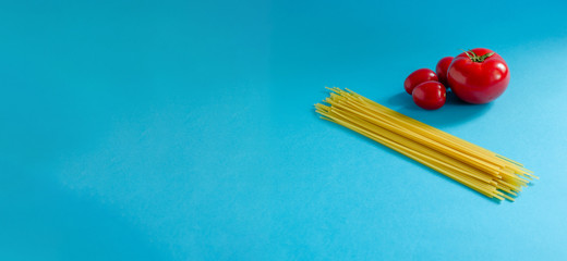 two tomatoes and spaghetti on a blue background, food delivery during the coronavirus pandemic