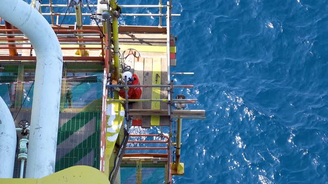KELANTAN, MALAYSIA - AUG 12th 2019 : Top view of unidentified offshore maintenance workers on scaffolding platform for removing corrosion and rust at the structure using air power tools.