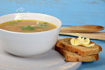 tripe soup in a white bowl next to bread and butter