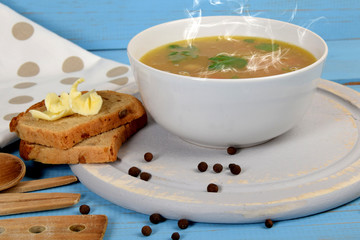 tripe soup in a white bowl next to bread and butter