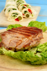 a piece of grilled steak accompanied by wrapped vegetables in a tortilla