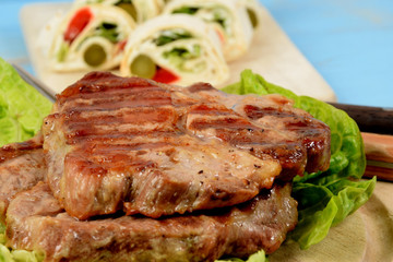 a piece of grilled steak accompanied by wrapped vegetables in a tortilla