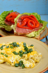scrambled eggs with chives, a colorful sandwich and tea on an old blue table