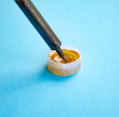 Soldering iron, tin, rosin on a blue background. Soldering iron in male hands. Macro. Repair of...