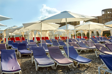 pebble beach with sunbeds and umbrellas against the blue sky