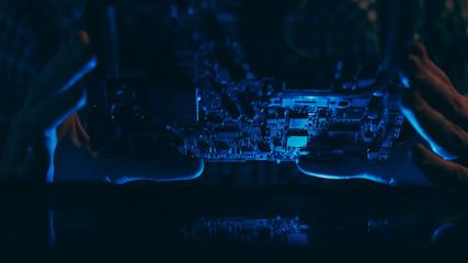 Microelectronics technology. Hardware diagnostics. Engineer examining motherboard.