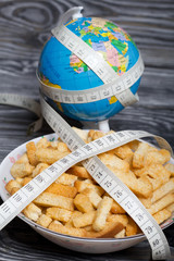 Globe wrapped with measuring tape. Near a cup with crackers. On brushed pine boards. Symbol of...