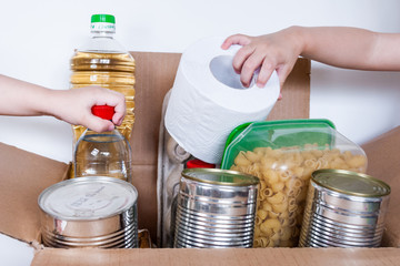 children's hands take food out of the box with donations
