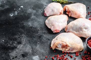 Raw chicken thigh with skin, organic meat. Black background. Top view. Copy space
