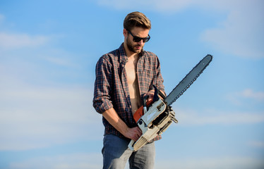 Naklejka premium Dangerous job. men brutality and sexuality. Job for real men. macho man chain saw tool. male work power saw. He fix everything. comfident worker. Mens power. sexy man sky background